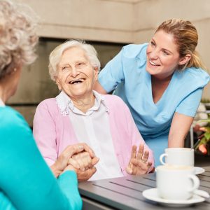 Senior Frauen lachen und haben Spaß im Altenheim beim Kaffee trinken
